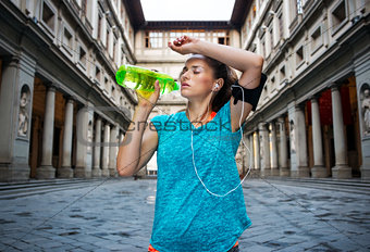 Fitness woman is drinking water while outdoors training