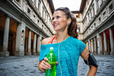 Portrait of happy fitness woman with bottle of water. Florence