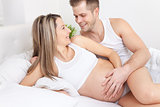Delighted young parents in bed expecting a baby