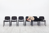 Office worker asleep on row of chairs