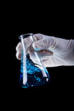 Hand holding chemical flask stirring blue liquid