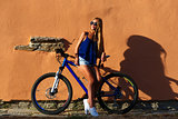 Pretty young hipster blonde girl posing with cycle