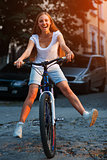 Young blonde stylish woman posing with bike