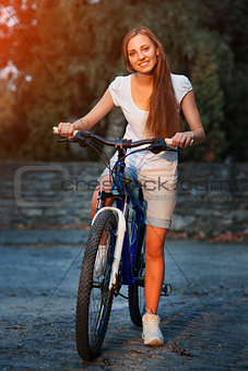 Young blonde stylish woman posing with bike