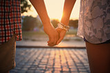 Loving couple holding hands while walking at sunset 