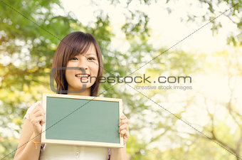 Young Asian college girl student holding blank chalkboard