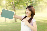 Asian female college student pointing at blank chalkboard