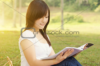 Young Asian college girl student reading book