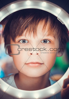 Surprised boy looking at the camera through a luminous circle as an astronaut