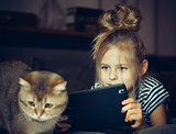 Beautiful girl holding a Tablet and looks at the cat