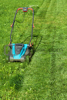 Freshly cut grass strips and blue lawnmower