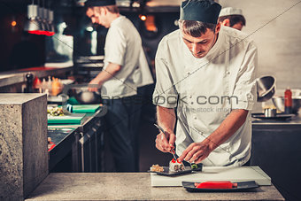 male cooks preparing sushi