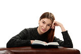Young woman with book leaning on leather furniture