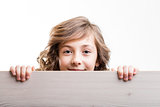 little girl looks from behind a board
