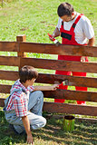 Father and son painting a garden fence
