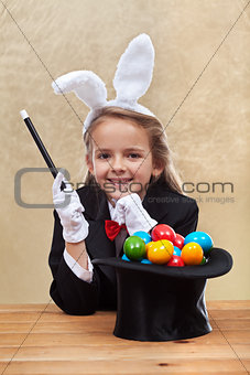 Happy magician girl making easter eggs with her powers