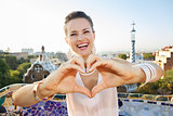 Woman tourist showing heart shaped hand in Park Guell, Barcelona