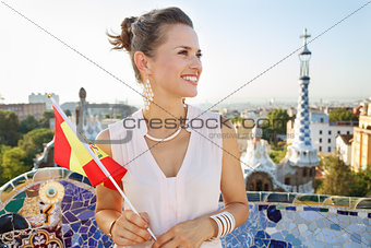 Smiling woman tourist with Spain flag in Park Guell, Barcelona