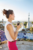 Seen from behind woman tourist with photo camera in Park Guell