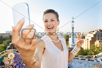 Woman showing victory and taking selfie with mobile, Park Guell