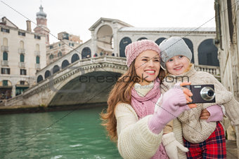 Smiling mother and daughter taking photos near Ponte di Rialto