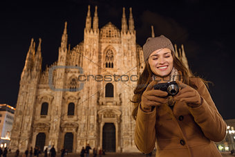 Woman looking on photos in camera near Duomo in evening, Milan