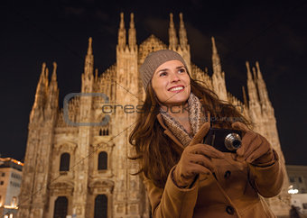 Smiling woman with photo camera near Duomo in evening, Milan