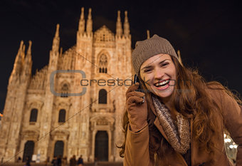Smiling woman talking cell phone near Duomo in evening, Milan
