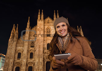 Happy woman writing sms in front of Duomo in evening, Milan
