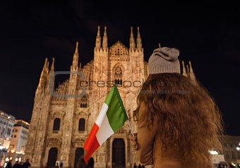Seen from behind woman with Italian flag near Duomo in evening