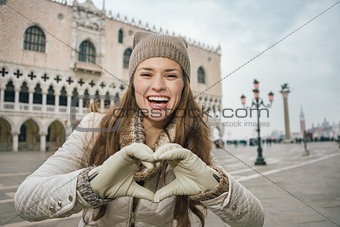 Woman tourist showing heart shaped hands on St. Mark's Square