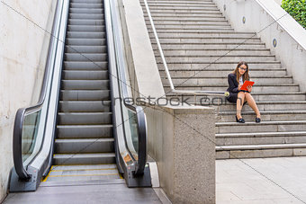 Office woman working in the stairs near scalator with tablet