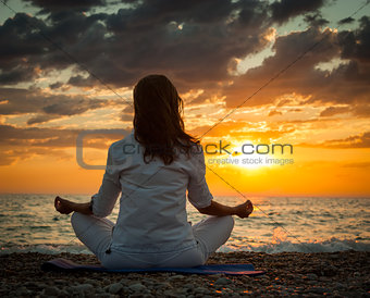 Woman Practicing Yoga by the Sea at Sunset