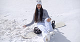 Attractive young woman sitting on her snowboard