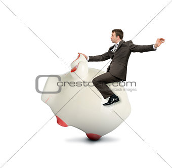 Businessman riding piggy bank