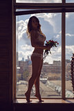 girl standing at the window in his underwear with flowers
