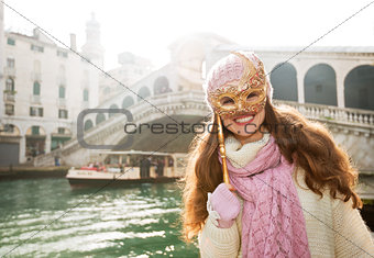 Smiling woman hiding behind Venice Mask near Rialto Bridge