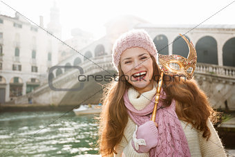 Smiling woman holding Venice Mask in the front of Rialto Bridge