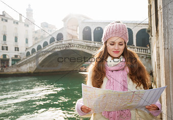 Happy woman tourist looking on map in the front of Rialto Bridge