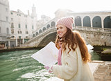 Woman tourist with map near Rialto Bridge looking on Grand Canal