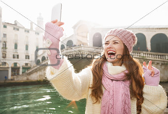 Woman tourist showing victory while taking selfie in Venice