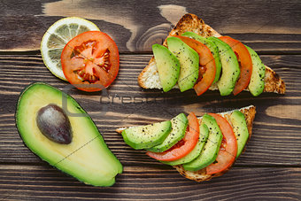Fresh healthy snacks with avocado, tomato and bread.