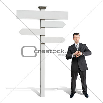 Businessman looking at his hand near road sign