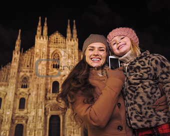 Mother and daughter talking smartphone near Duomo in Milan