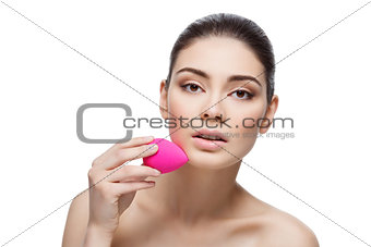 Beautiful girl applying foundation with sponge