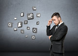 Young man in business suit, thinking about media, on concrete wall background. Business concept