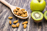 Fresh kiwi, apples and almonds on wooden background. Concept of healthy lifestyle