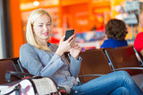 Female traveler using cell phone while waiting.