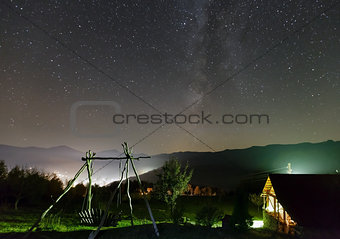 Starry night sky over mountain village. 