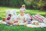 Happy child sits on a meadow looks to Easter decoration
